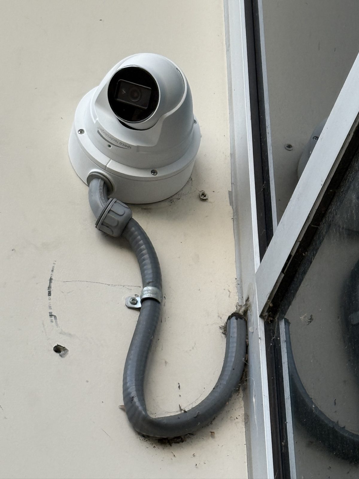 Weatherproof camera with proper conduit on a commercial exterior.