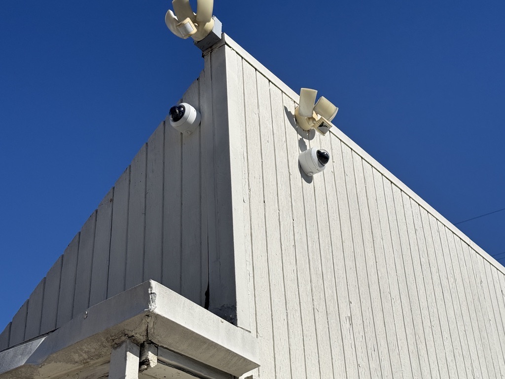 New exterior turret cameras installed high on a building corner overlooking a parking lot
